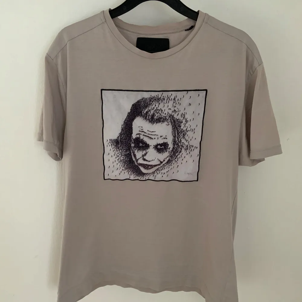 En limitato t-shirt med en bild på jokern. Tröjan är i fint skick och har inga defekter. Färgen är vit-beige. Hör av er vid funderingar. T-shirts.