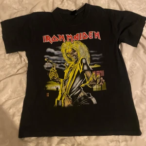 Svart Iron Maiden t-shirt - Säljer en svart Iron Maiden t-shirt med ett coolt tryck av Killers albumet. Den har en normal passform och är gjord i bomull, vilket gör den bekväm att bära. Perfekt för konserter eller vardagsbruk! Hittade inga lappar tyvärr❣️