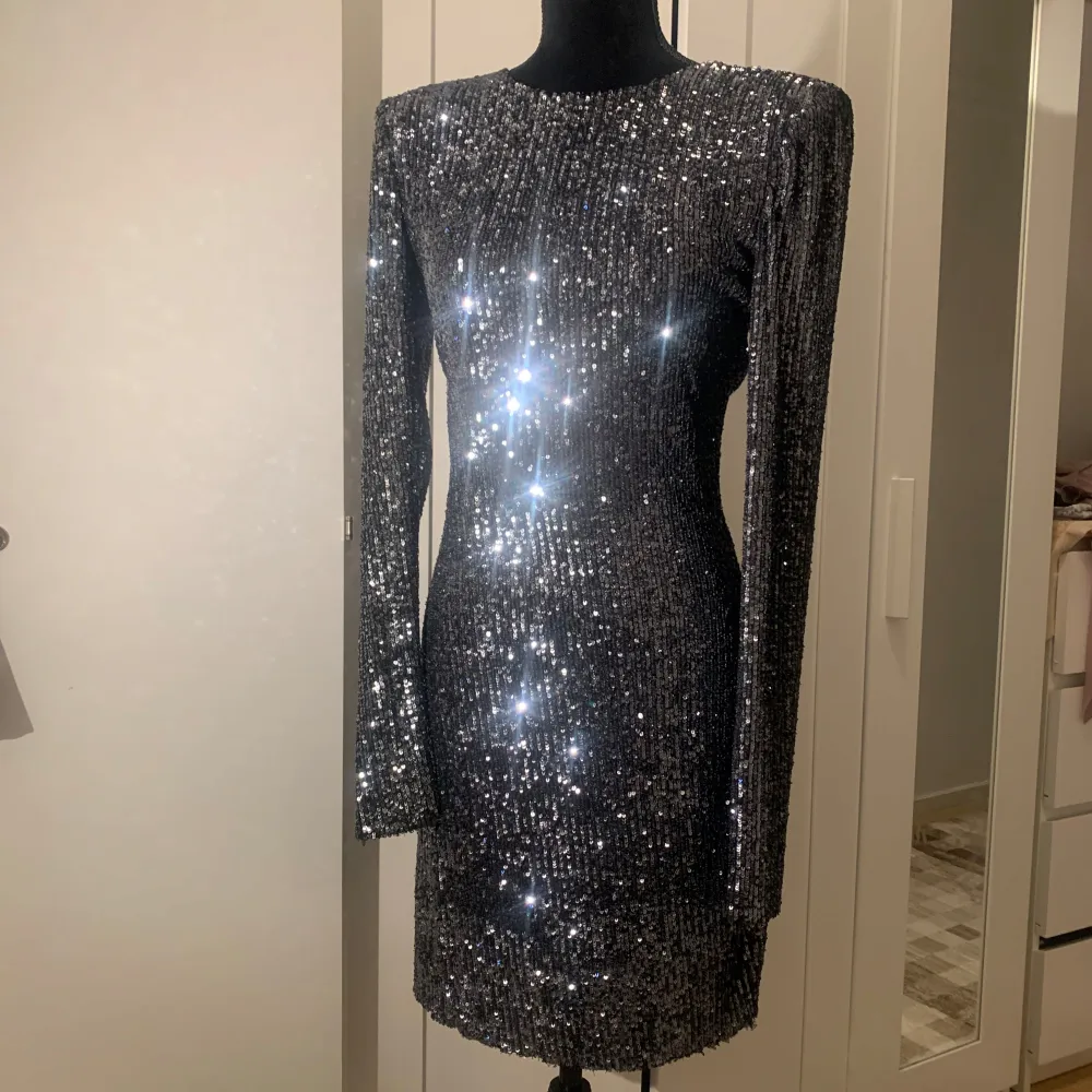 Säljer en superglittrig svart klänning som verkligen fångar ljuset! Den är långärmad och perfekt för en fest eller nyårsafton. Klänningen har en tight passform som framhäver figuren och är täckt av glittriga paljetter. Ett måste för den som vill sticka ut!. Mekot.
