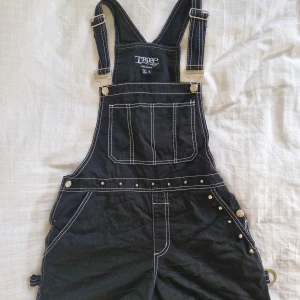 Hängselbyxor Tripp NYC - Supercoola hängselshorts från Tripp NYC! 🖤 Många fickor, nitar och anpassningsbara axelband. 100% bomull. Sparsamt använda, inga synliga defekter! Köpte dem second hand för något år sedan, säljer då jag inte använder dem. Pris är diskuterbart! 