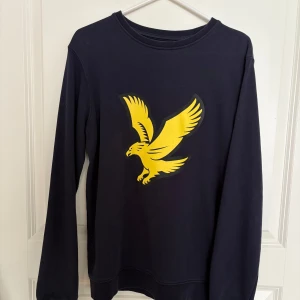 Lyle & Scott tröja i marinblått, strlk 14-15 år - Mörkblå tröja med Lyle & Scott-tryck på framsidan. Storlek 14/15 år, motsvarar ca 170. Bra skick, inga defekter. Djur- o rökfritt hem.