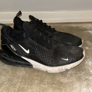 Svarta Nike Air Max sneakers - Säljer ett par svarta Nike Air Max sneakers i välanvänt skick. De har en snygg och sportig design med vit sula och den klassiska Nike-loggan på sidan. Perfekta för både träning och vardagsbruk. Skorna har en bekväm passform och är lätta att matcha med olika outfits.