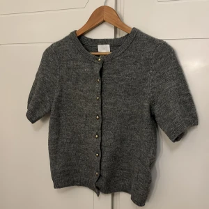 Kortärmad kofta - Säljer denna oanvända konfan från hm i storlek S. Grå med guldknappar🌸
