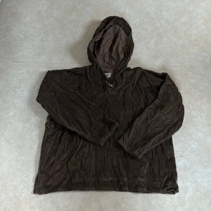 Brun huvtröja - En brun huvtröja med en ficka på magen. Tröjan har en träknapp i huvan. 