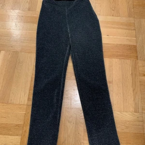 Svarta glittriga byxor - Snygga svarta byxor med glittrig finish, perfekta för festliga tillfällen. De har en tight passform och är högmidjade, vilket ger en smickrande siluett. Materialet är stretchigt och bekvämt, vilket gör dem lätta att bära hela kvällen. Perfekta för att sticka ut på festen! ✨