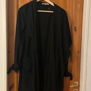 Lång kappa - Lång svart kappa. Ganska tunt material, perfekt till våren! Lite fläckig men går nog lätt bort i tvätten