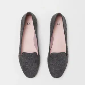 Snygga och stilrena grå loafers från H&M.Ett par loafers med ripsband runt kanten. Foder och innersula i satin. Yttersula i gummi. Mörk gråmelerad. Perfekt för vardagligt bruk.