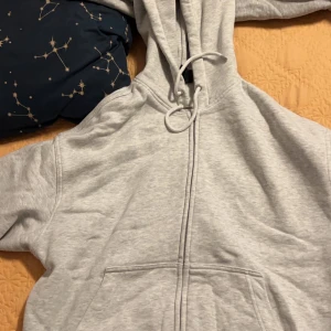 Grå hoodie från H&M - Säljer en grå ziphoodie från H&M i oversized fit. Den har en dragkedja framtill och en mysig huva med snörning. Perfekt för kyliga dagar eller bara för att chilla hemma. Den är i bra skick och superbekväm!