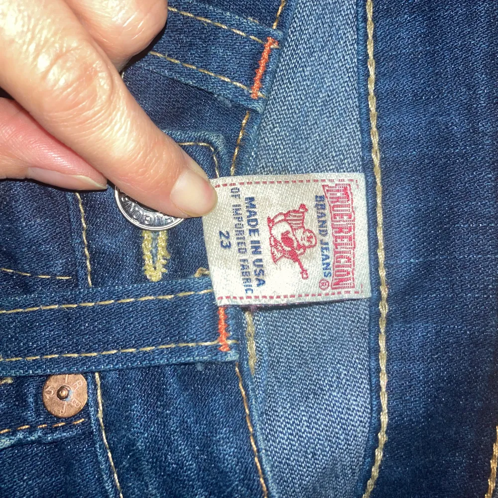 Säljer ett par snygga mörkblå jeans från True Religion i storlek 23. De har en klassisk femficksdesign med coola detaljer på bakfickorna och en knappgylf. Perfekta för både vardag och fest! 🕺Avklippta, innersöm 71 cm, yttersöm 89 cm. Midja 32cm rakt över. Mycket fint skick!. Farkut & Housut.