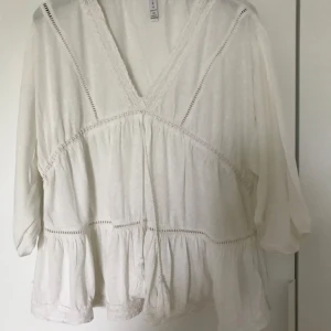 Vacker vit topp  - V ringad vit spetstopp från Amisu med tofsar. Storlek XS men stor i storleken. Mycket obetydligt använd.