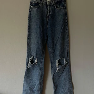 Blå jeans från NA-KD Reborn - Säljer ett par blå jeans från NA-KD Reborn i storlek 38. De har en avslappnad passform med slitna detaljer på knäna. Perfekta för en casual outfit! De är högmidjade och är ganska långa i benen🖤