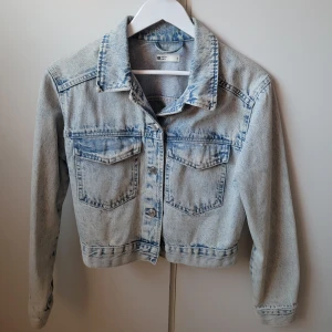 Ljusblå jeansjacka från Gina tricot - Säljer en snygg ljusblå jeansjacka från gina tricot i storlek S. Jackan har en klassisk design med knappar framtill och två bröstfickor. Perfekt för vår och sommar, och ger en cool vintage vibe. Passar till allt från klänningar till jeans! 🎀