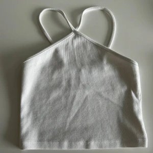 Vit ribbad topp från Zara - Säljer en superfin vit ribbad topp från Zara. Inte använd en enda gång. Den har smala axelband och en enkel design som gör den lätt att matcha med olika outfits. 