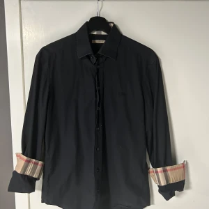 Burberry skjorta  - Säljer en tvär fet burberry skjorta i storlek M. Den är äckta och kvitto finns. Sitter bra och har burberrys klassiska rutmönster i kragen och vid ärmarna. Kan bytas mot något annat roligt. Det är en herr skjorta.