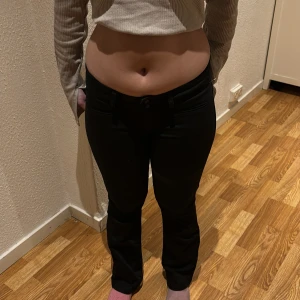Svarta byxor med knappar - Säljer ett par svarta byxor i bra skick. Lågmidjade och bootcut (liknande gröna hm byxorna) De har en tight passform och är högmidjade med knappar framtill. Perfekta för både vardag och fest! 🖤
