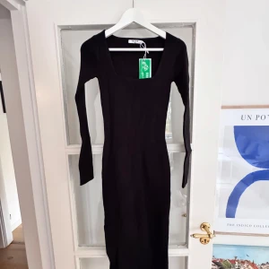 Stickad/ribbad klänning - Vadlång klänning med slits i sidan från Nakd. Storlek S. Oanvänd med prislapp. 