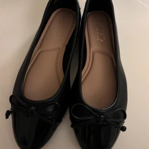 Svarta ballerinaskor med rosett - Snygga svarta ballerinaskor  med en elegant rosett på tån. Perfekta för en stilren look och verkligen bekväma att bära hela dagen. Veganska och i storlek EU 39.