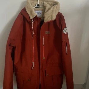 Röd jacka med teddyfoder från Picture - Säljer denna snygg orange-röda jackan från Picture med mjukt teddyfoder i huvan. Den är sparsamt använd utan några skador. Säljer den då den inte längre används. Hör gärna av er om ni har frågor! 