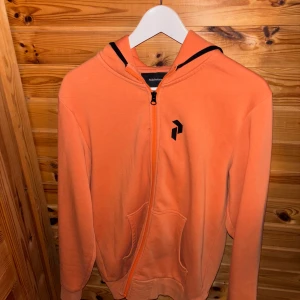 Orange hoodie med dragkedja - Säljer en snygg orange hoodie från Peak Performance. OTROLIGT bekväm bara använd en fåtttal gånger  