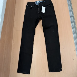 Svarta slim fit byxor från Dressmann - Säljer ett par klassiska svara jeans från Dressmann. De har en slim passform och är tillverkade i ett slitstarkt denimtyg. Perfekta för en avslappnad stil. Är i nytt skick aldrig använda.