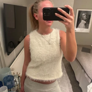 Vit fluffig ärmlös topp - Säljer en supermjuk och fluffig vit ärmlös topp.Toppen är i ett syntetmaterial som ger en härlig känsla. 