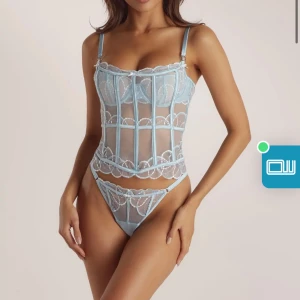 Ljusblå spetskorsett och trosor  - Elegant ljusblå korsett med spetsdetaljer och tunna axelband. Den har en genomskinlig design med vackra broderade mönster och en feminin siluett samt trosor som tillhör. Perfekt för speciella tillfällen. I nyskick med lappar kvar. Nypris 1200kr