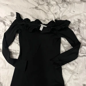 Off shoulder topp från NLY Trend - Off shoulder topp från NLY Trend med volangdetaljer vid halsringningen. Toppen har långa ärmar och en tight passform. 