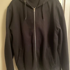 Svart hoodie från Weekday - Säljer en stilren svart hoodie från Weekday i storlek L. Den är i väldigt bra skick då den är använd bara några gånger och säljer på grund av att den var för stor för mig.