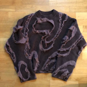 Brun tröja med slitna detaljer - Unik brun tröja med slitna detaljer och en cool, edgy look. Perfekt för dig som vill sticka ut med en trendig stil. Tröjan har långa ärmar och en rund halsringning.