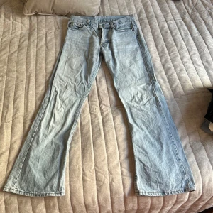 Ljusblå jeans bootcut flare - Säljer ett par ljusblå bootcut jeans med klassisk femficksdesign. Jeansen har en lågmidjad passform och är perfekta för en avslappnad stil. Vintage denim stil. Står storlek M men skulle säga mer S
