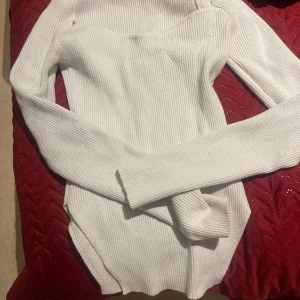 Vit ribbad tröja - Säljer en stilren vit ribbad tröja med långärmad design. Perfekt för lager-på-lager under kyligare dagar. Tröjan har en figurnära passform och är tillverkad i ett mjukt material.