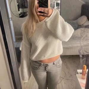 Vit stickad croppad tröja - Säljer en mysig vit stickad tröja med croppad passform. Tröjan har långa ärmar och en avslappnad stil, perfekt för kyligare dagar. Passar bra till jeans eller kjol för en trendig look.