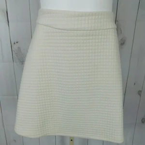 Crémefärgad quiltad kjol från Banana Republic - Snygg quiltad kjol från Banana Republic. Kjolen har en dragkedja baktill och ett stilrent rutmönster. Perfekt för en chic och modern look.Storleken på etiketten är 4, vilket är en amerikansk storlek. I Sverige, som använder EU-storlekar, motsvarar detta vanligtvis EU 36/37