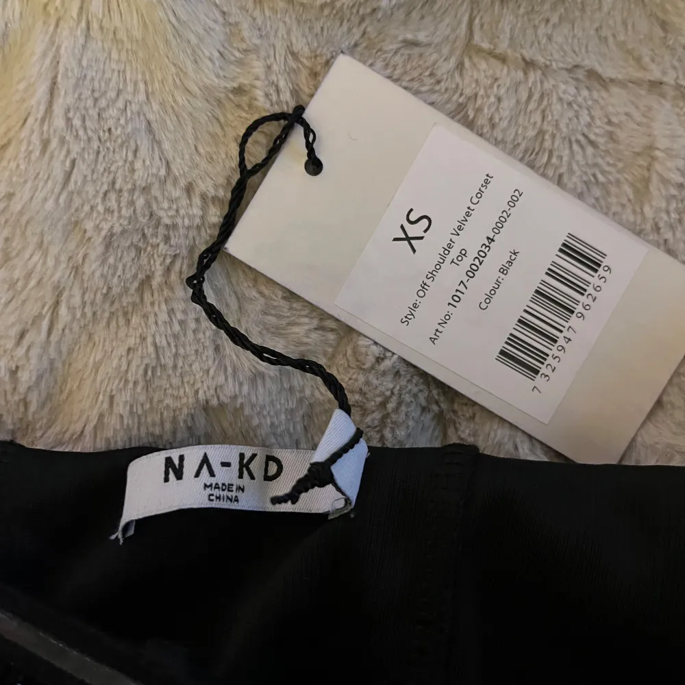 Snygg svart offshoulder topp med glittriga detaljer. Toppen har en volangkant och är tillverkad i ett mjukt material som ger en elegant look. Perfekt för en kväll ute eller en speciell tillställning.. Yläosat.