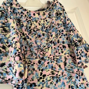 Mönstrad klänning från Lindex  - Säljer en färgglad klänning från Boohoo med ett abstrakt mönster i rosa, blått och svart. Klänningen har korta ärmar och en lös passform, perfekt för en somrig look.