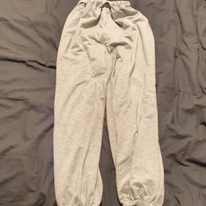 Grå mjukisbyxor med text - Säljer ett par grå mjukisbyxor med elastisk midja och texten 'STOP LOOKING AT MY BUTT' i vitt på baksidan.