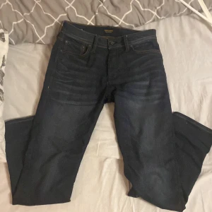 Mörkblå jeans från Jack & Jones - Snygga mörkblå jeans från Jack & Jones i modellen Slim Straight / Tim. De har en klassisk femficksdesign och en läderpatch med logotyp baktill. Perfekta för en stilren look. W29 L30