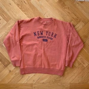 New York Rugged Issue Sweatshirt - Vintage New York Rugged Issue sweatshirt i mycket fint skick. Härlig passform och mysig som ett extra lager. Unik korallfärg med brodyr på bröstet. Storlek M/L. Mått: Bröst: 63 cm, Längd: 66 cm, Axelbredd: 57 cm, Ärmlängd (från axeln): 61 cm. 