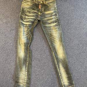 Säljer ett par snygga jeans från Dsquared2. De är blå med en cool slitningseffekt som ger dem en trendig look. Jeansen har en skinny passform och är perfekta för både vardag och fest. De har klassiska fem fickor och en dragkedja framtill.