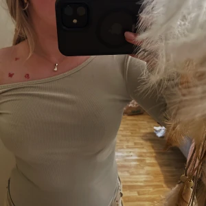 Beige topp  - En snygg beiga top, med snedskuren axel, sitter fint och formar snyggt, och väldigt skönt tyg. I storlek XS