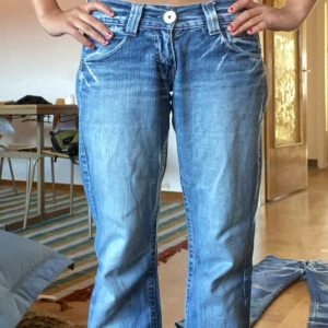 Blå jeans från EDC - Säljer ett par snygga blå jeans från EDC esprit. De är i en ljusare wash och har coola slitningar samt broderade detaljer på bakfickorna. Jeansen är i en utsväng passform och är lågmidjade. Perfekta för en avslappnad vardagslook! (tyvärr slitna på benslutet som ni ser på sista bilder)