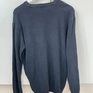 Mörkblå tröja från Oscar Jacobson - Säljer en stilren mörkblå tröja från Oscar Jacobson. Tröjan är tillverkad i 100% bomull och har en rund halsringning. Perfekt för en klassisk och bekväm look. Tillverkad i Italien.