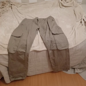 Ljus militä cargobyxafrån Gina Tricot - Säljer ett par beige cargobyxor från Gina Tricot. Byxorna har flera praktiska fickor och en avslappnad passform. Perfekta för en casual look.