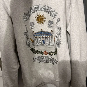 Grå sweatshirt från Casablanca - Säljer en grå sweatshirt från Casablanca med ett detaljerat tryck av antika motiv och texten 'Equipment Sportif'. Perfekt för en stilren och sportig look. Aldrig använt pågrund av storlek, Kvitto och allt annat finns med! Ny pris -:5499kr