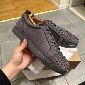 Mörkgrå loubs storlek 42 - Snygga grå sneakers med nitar på tå och häl. Skorna har en röd sula och snörning framtill. Perfekta för att ge en edgy touch till din stil. Storlek 42 pris kan diskuteras.