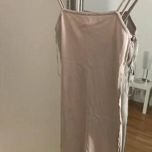 Beige ribbad klänning - Säljer en stilren beige ribbad klänning med smala axelband. Perfekt för en minimalistisk look. Klänningen har en enkel och elegant design som passar till många tillfällen.