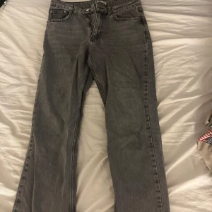 Grå jeansbyxor - Snygga grå jeansbyxor med klassisk femficksdesign. De har en rak passform och är perfekta för en avslappnad stil. Byxorna har en knapp och dragkedja framtill.