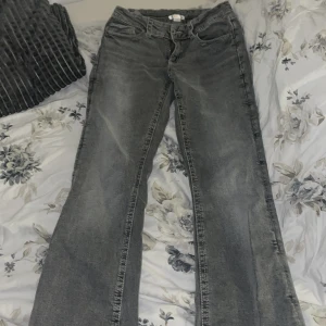 Grå jeans från Gina Tricot Young  - Snygga grå bootcut jeans från Gina Tricot Young med en klassisk femficksdesign och knappdetaljer på fickorna. Byxorna är i storlek 164, om ni vill ha mer exakta mått kan ni kontakta mig. Säljer pga fel storlek och har aldrig använt dem.