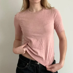 Rosa kortärmad tröja - Säljer en söt rosa kortärmad tröja med rund halsringning. Tröjan har en ribbad kant vid ärmslut och nederkant, vilket ger en fin passform. Perfekt för en avslappnad stil.