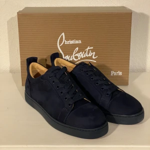 Christian Louboutin mörkblå - Snygga mörkblå sneakers från Christian Louboutin i mocka med den ikoniska röda sulan. Skorna har snörning och en stilren design som passar perfekt för en trendig look. Levereras med originalförpackning och dustbag. Finns inte din storlek? Vi kan fixa alla storlekar bara att höra av sig så löser vi de du vill ha! Vi kan även fixa alla skor, tröjor, jackor, västar osv till riktigt bra pris bara att skicka bild på vad du söker och storlek så ska vi göra de vi kan!/// Es Clothing se mindre